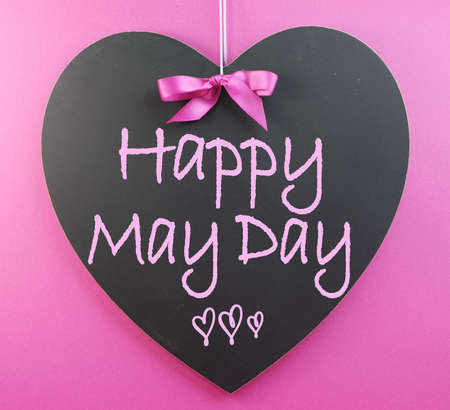 Happy May Day handwriting greeting on heart shaped blackboard on pink background の写真素材