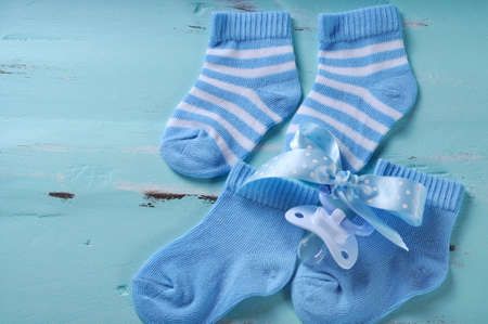 Baby boy nursery blue and white socks and dummy pacifier, with copy space, on aqua vintage shabby chic background for baby shower or newborn girl greeting card の写真素材