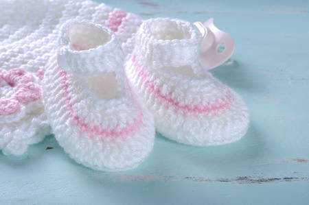 Baby girl nursery pink and white stripe wool booties, bonnet and pacifier dummy close up 