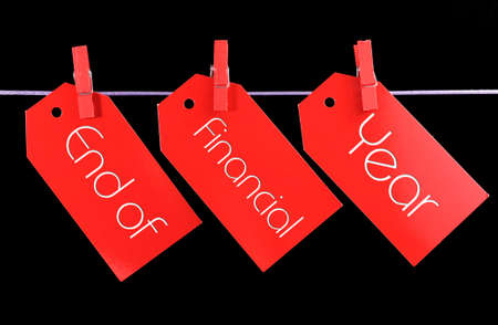 End of Financial Year red ticket sale tags hanging from pegs on a line against a black background.の写真素材