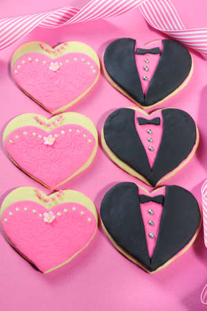 Delicious wedding party bridesmaids and groomsmen pink, white and black heart shape biscuit cookies bridal table favors on pink background の写真素材