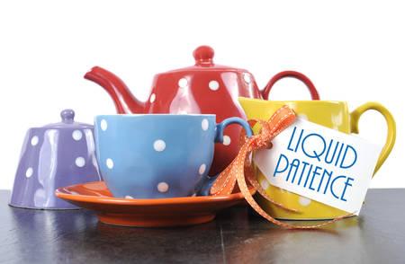 Red, blue, yellow, orange and purple polka dot tea set with teapot, milk jug creamer, sugar bowl and tea cup with sample text Liquid Patience for morning or afternoon coffee break.の写真素材