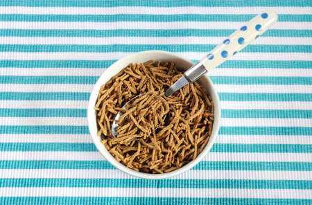 Healthy diet high dietary fiber breakfast with bowl of bran cereal on aqua blue and white place mat.の写真素材