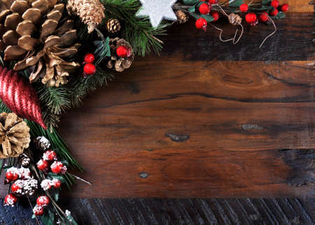 Traditional Happy Holidays and Christmas background with pine cones and festive ornaments on dark recycled wood with copy space for your text here.の写真素材