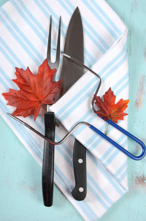 Thanksgiving roast turkey carving utensils set with blue stripe apron on vintage shabby chic table top. Vertical overhead.の写真素材