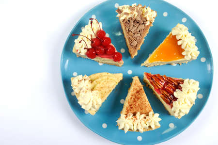 Thanksgiving apple, pecan, cherry, caramel, pumpkin spice and chocolate cream cheesecake pie, on blue polka dot platter against a white table, with copy space.の写真素材