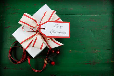 Christmas holiday background with red, white gift against a vintage style dark green recycled wood...