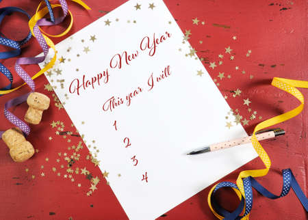 Happy New Year Resolutions planning and goal list on dark red wood background with gold stars and festive decorations.の写真素材