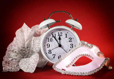 Happy New Year clock, masquerade party mask and festive white flowers on ared background.の写真素材