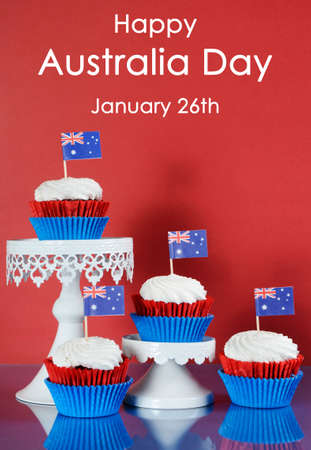 Happy Australia Day, January 26th, party food with red, white and blue cupcakes and Australian flags on red and blue background with sample text greeting.の写真素材