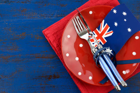 Happy Australia Day, January 26, theme table setting with red polka dot plate and Australian flag decoration on dark blue wood background.の写真素材