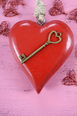 Happy Valentines Day key to my heart concept with large hanging heart on shabby chic pink wood background.の写真素材