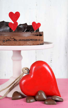 Valentine chocolate mousse layer gateau cake with chocolate shards decoration and red hearts on shabby chic vintage white and pink wood background.の写真素材