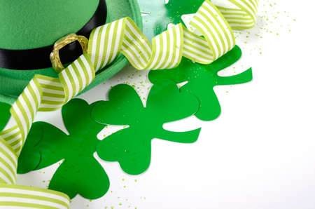 Happy St Patricks Day leprechaun hat with shamrocks and party ribbons on white table.