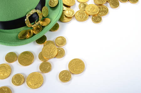 Happy St Patricks Day leprechaun hat gold chocolate coins on white table.の写真素材