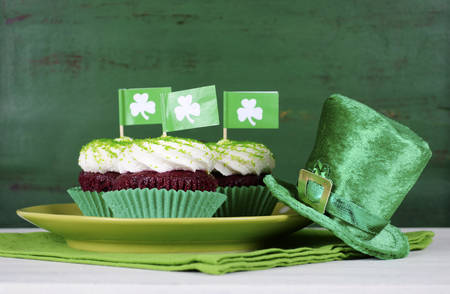 Happy St Patricks Day cupcakes with green theme decorations on vintage style green wood background.の写真素材
