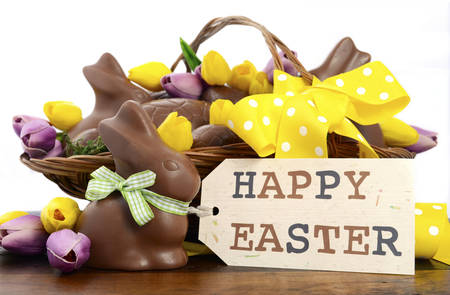 Happy Easter chocolate hamper of eggs and bunny rabbits in large basket with yellow and pink purple...