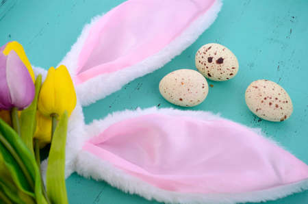 Happy Easter pink bunny ears on aqua blue wood table.の写真素材