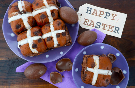 Easter chocolate hot cross buns on dark wood table.