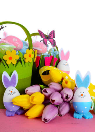 Happy Easter egg hunt baskets with tulip flowers and eggs with bunny ears and faces on a pink wood...