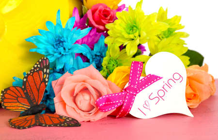 Happy Springtime Spring colorful roses and daisy flowers on pink wood table. with yellow vintage style garden watering can and butterfly closeup.の写真素材