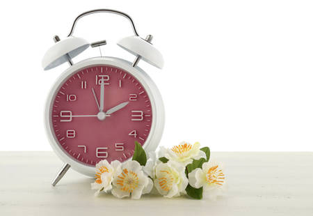 Daylight Saving Time concept with spring theme pink retro style alarm clock on white wood...