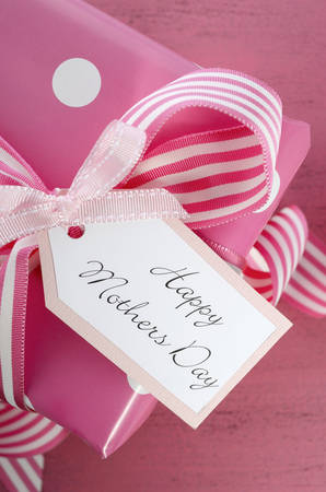 Happy Mothers Day pink polka dot gift with pink and white stripe ribbon and gift tag on vintage pink wood table - overhead closeup.の写真素材