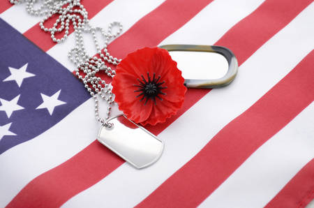 USA Memorial Day concept with dog tags and red remembrance poppy on American stars and stripes flag.の写真素材