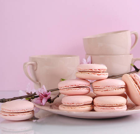 Plate of pink macaron cookies with vintage cups and plates on pink and white background.の写真素材
