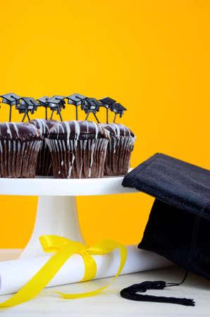 Happy Graduation Day party chocolate cupcakes with graduation cap hat topper decorations, in yellow, black and white party theme.の写真素材