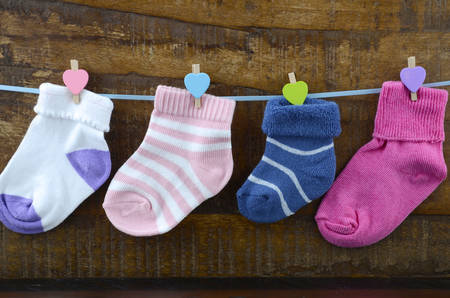 Happy Childrens Day concept with childrens socks hanging from pegs on a line on a dark wood background.の写真素材