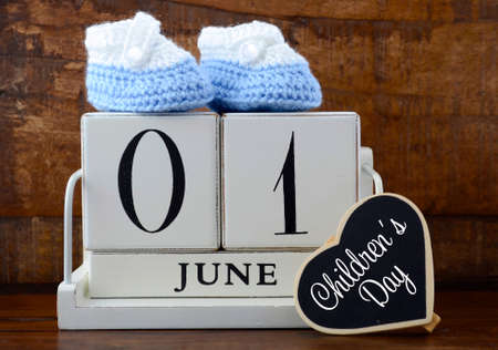 International Childrens Day concept with June First Calendar and child booties on dark wood rustic background.の写真素材