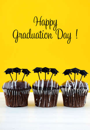 Happy Graduation Day party chocolate cupcakes with graduation cap hat topper decorations, in yellow, black and white party theme.の写真素材
