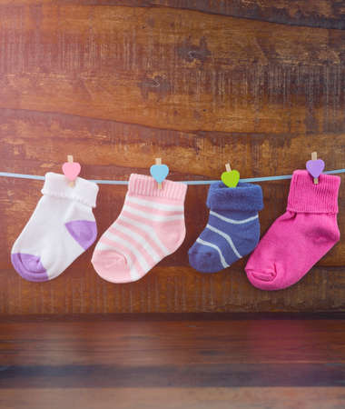 Happy Children Day concept with children socks hanging from pegs on a line on a dark wood , with applied retro filters and lens flare sun beam.の写真素材