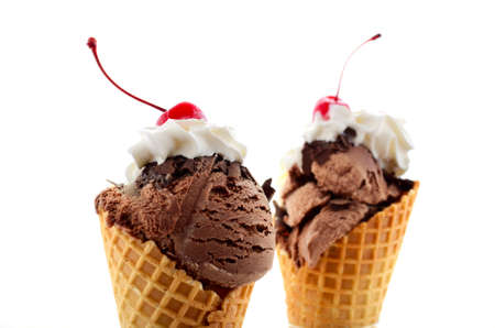 Summer concept chocolate and vanilla ice cream wafer cone with whipped cream and cherry with stem on top.の写真素材