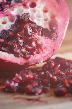 Close up of seeds of pomegranate fruit on vintage wood background, with applied filters and added lens flare.の写真素材