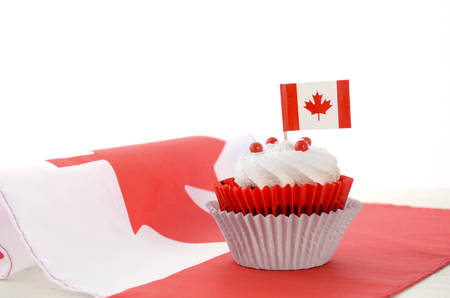Happy Canada Day celebration cupcake with red and white Canadian maple leaf flag on white wood table.の写真素材