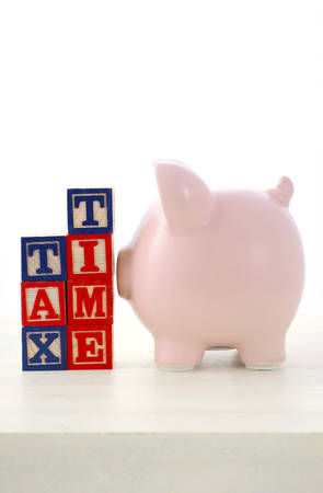 End of Financial Year Savings Concept with piggy bank, building blocks with tax time on white wood table.の写真素材