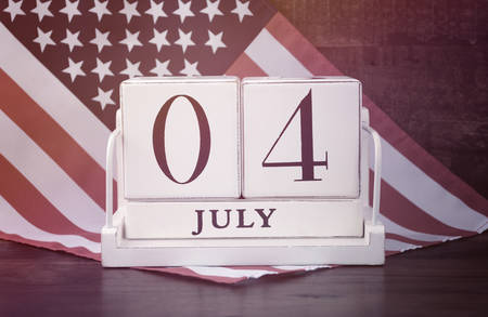 Fourth of July vintage wood calendar with flag on dark wood rustic background, with applied retro style filters.の写真素材