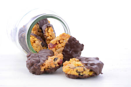 French style Florentine biscuits falling out of glass cookie jar on white shabby chic table.