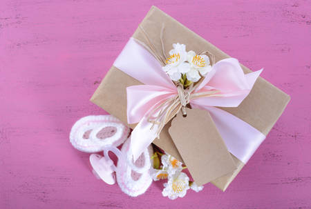 Baby shower Its a Girl natural wrap gift with gift box, baby booties and dummy on pink shabby chic rustic wood table.の写真素材