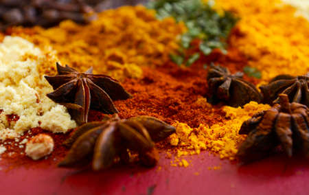 Colorful cooking spices and herbs on vintage red wood table with close up macro on star anise.の写真素材