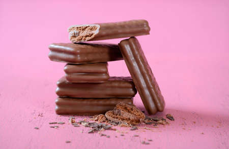 Stack of acrobatic chocolate cookies in fun compositions on wood table and pink background.の写真素材