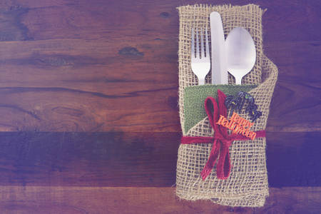 Rustic Halloween table place setting with burlap wrapped cutlery on dark wood table with applied retro vintage filters.の写真素材