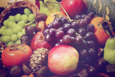 Thanksgiving Fall closeup of fruit, vegetables, pine cones, nuts and cornucopia with added retro vintage style filters.の写真素材
