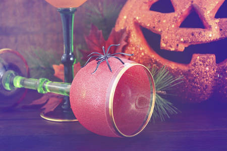 Happy Halloween table with Jack O Lantern pumpkin with party wine goblets on rustic dark wood vintage background with added vintage style filters.の写真素材