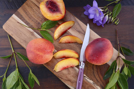 Fresh nectarines, cut and whole, on chopping board against a rustic wood background.の写真素材