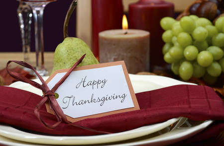 Happy Thanksgiving table setting in classic rustic colors on wood table with cornucopia centerpiece, candles and fruit.の写真素材