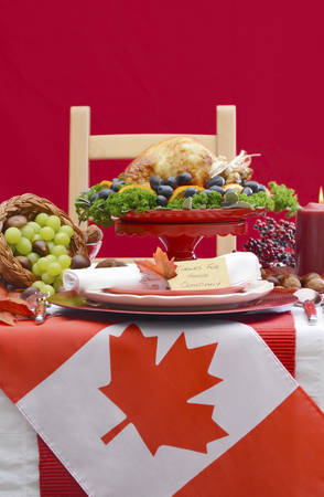 Red and white Canadian theme Thanksgiving Table setting with flag and Roast Turkey Chicken on large platter centerpiece .の写真素材