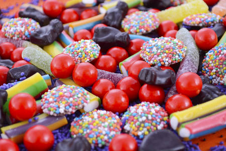 Bright colorful Halloween theme candy background with chocolate freckles, candy worms, orange and purple theme lollies.の写真素材
